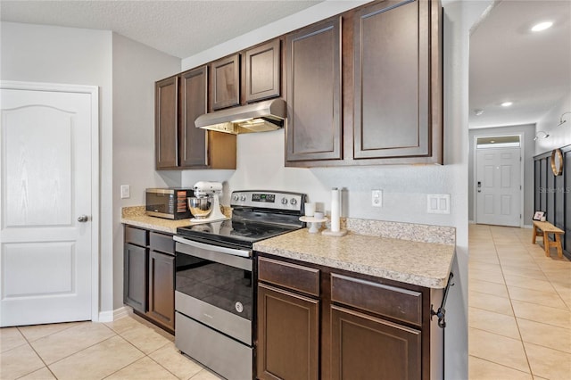 kitchen with dark brown cabinets, under cabinet range hood, light countertops, appliances with stainless steel finishes, and light tile patterned flooring