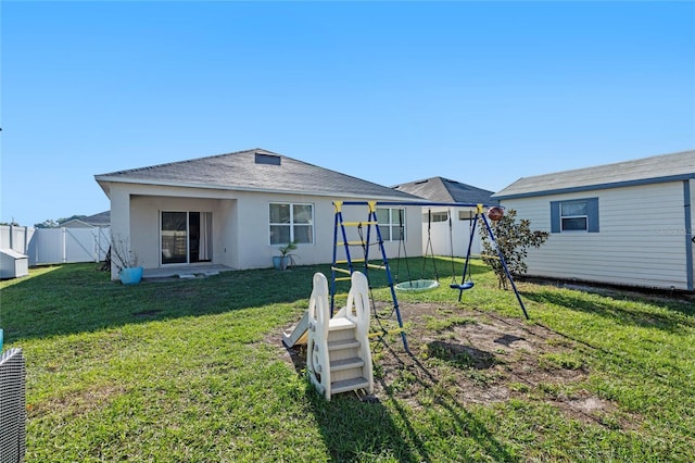 rear view of house featuring stucco siding, a yard, and fence