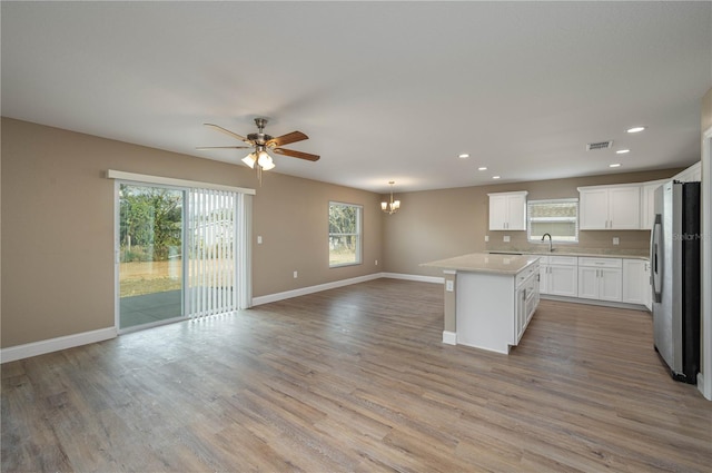 kitchen with light wood-style flooring, open floor plan, freestanding refrigerator, light countertops, and baseboards