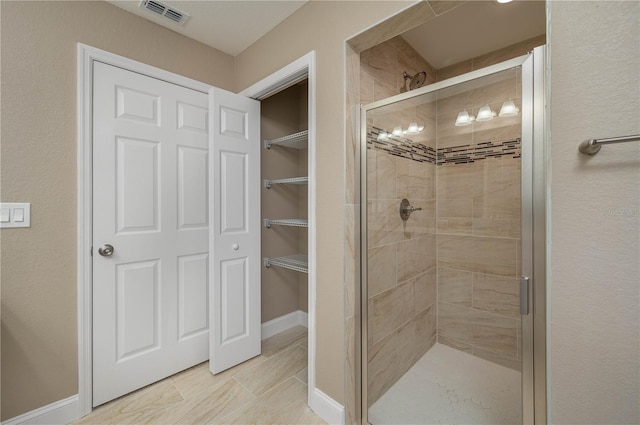 bathroom with visible vents, baseboards, a walk in closet, and a shower stall