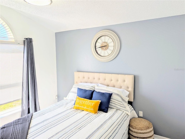 bedroom featuring baseboards, a textured ceiling, and vaulted ceiling