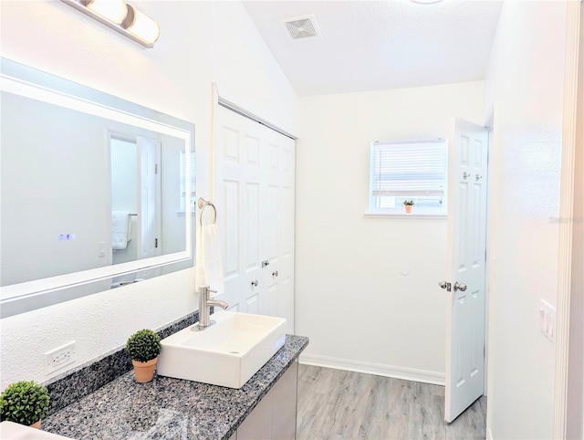 bathroom featuring visible vents, baseboards, wood finished floors, and vanity