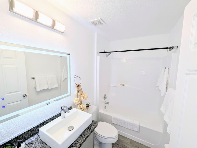 bathroom featuring vanity, a textured ceiling, visible vents, shower / bath combination, and toilet