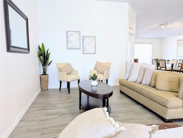 living area featuring visible vents, baseboards, light wood-style flooring, and track lighting