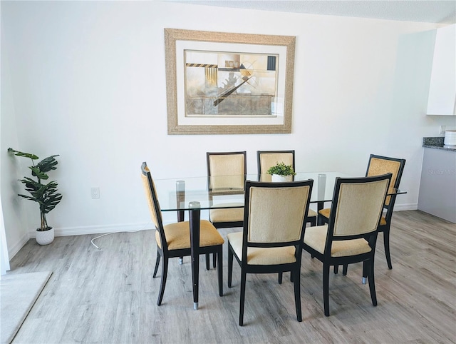 dining room featuring light wood-type flooring and baseboards