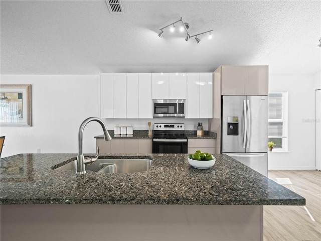 kitchen with visible vents, light wood-type flooring, stainless steel appliances, a textured ceiling, and a sink