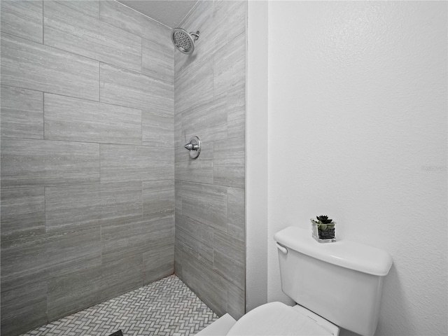 full bath with tiled shower and toilet