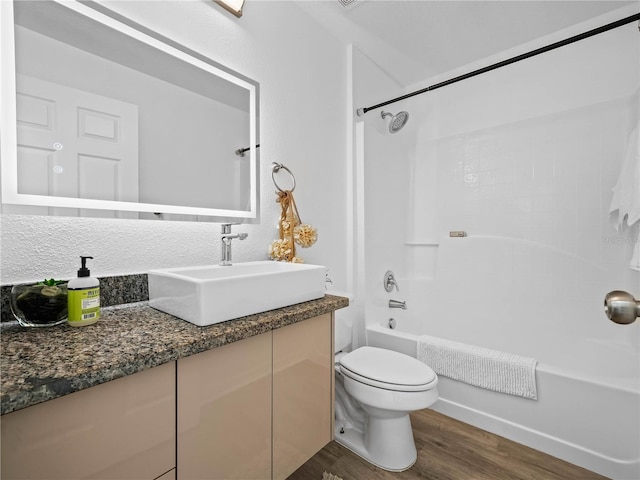 full bath with bathing tub / shower combination, wood finished floors, vanity, and toilet