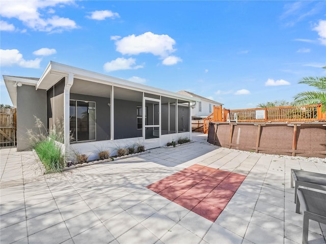 back of house with stucco siding, fence, a patio area, and a sunroom