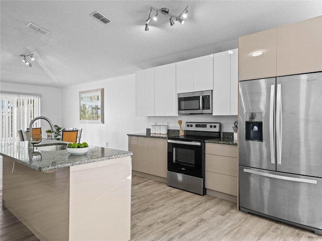 kitchen with visible vents, light wood-style flooring, a sink, appliances with stainless steel finishes, and a textured ceiling