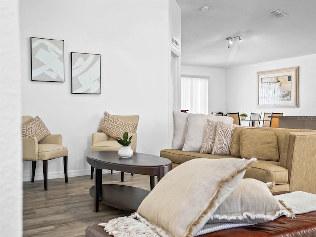 living area featuring track lighting, wood finished floors, visible vents, and baseboards