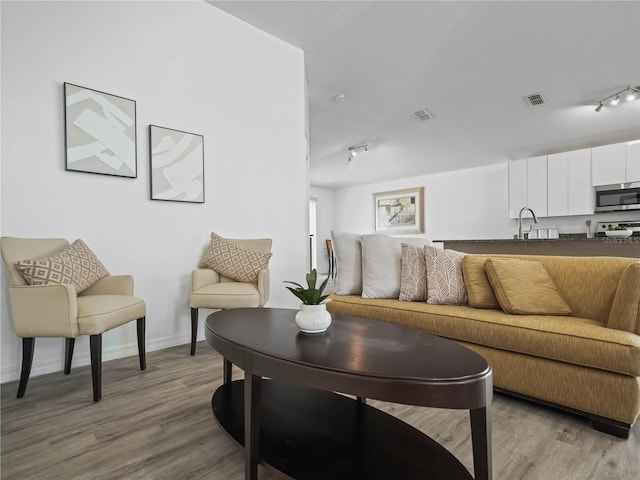 living room featuring track lighting, wood finished floors, and visible vents