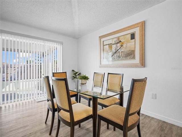 dining area featuring baseboards, a textured ceiling, and wood finished floors