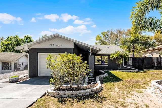 view of front of home featuring a front lawn, fence, concrete driveway, stucco siding, and a garage