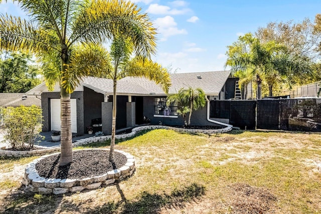 rear view of property featuring stucco siding, a yard, and fence