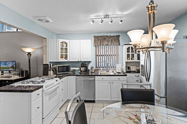 kitchen with a sink, stainless steel appliances, glass insert cabinets, and white cabinetry