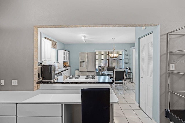 kitchen featuring pendant lighting, light tile patterned flooring, a notable chandelier, stainless steel fridge, and a sink