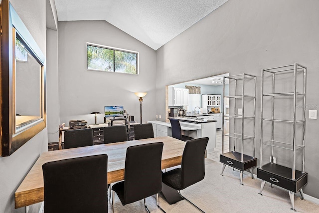 dining area with light carpet, a textured ceiling, and vaulted ceiling