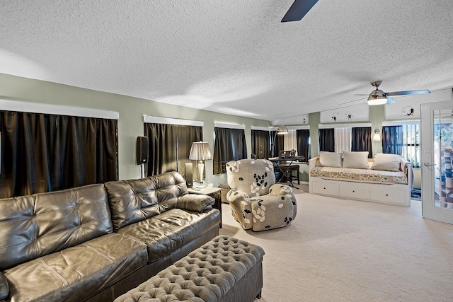 living room with a ceiling fan, light colored carpet, and a textured ceiling