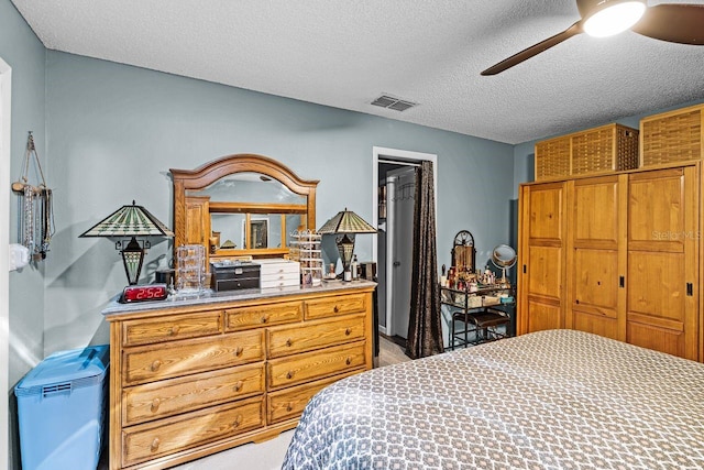 bedroom with a ceiling fan, visible vents, and a textured ceiling