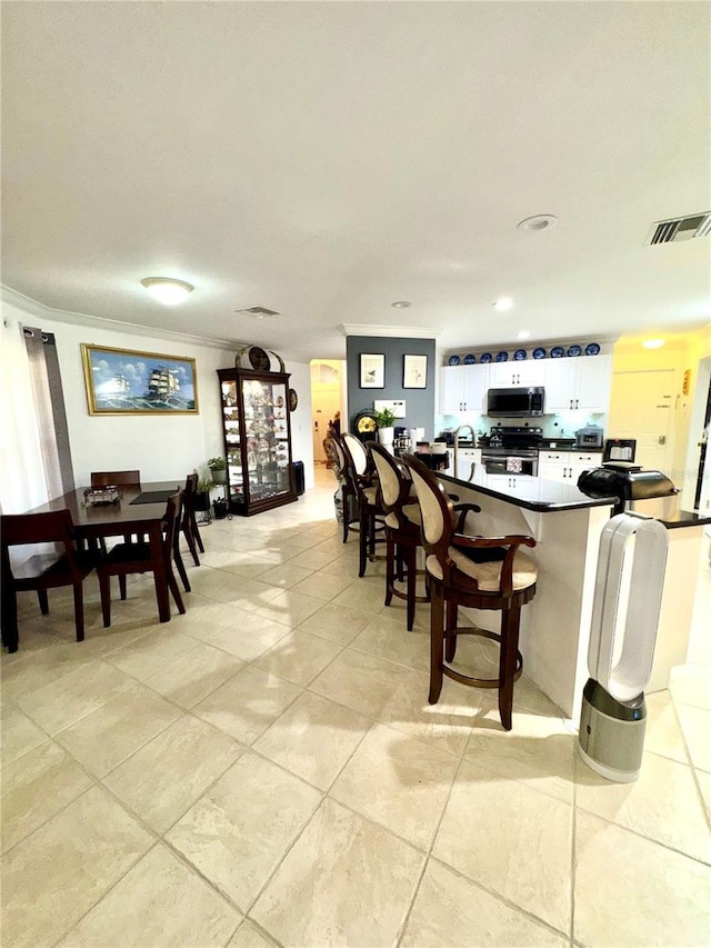 interior space with light tile patterned floors, visible vents, and crown molding