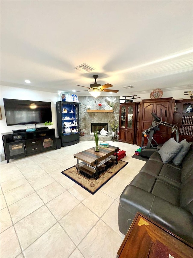 living area with light tile patterned floors, visible vents, a fireplace, and a ceiling fan