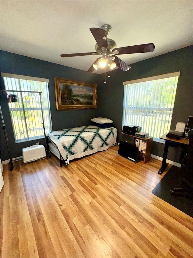 bedroom with a ceiling fan, baseboards, and wood finished floors