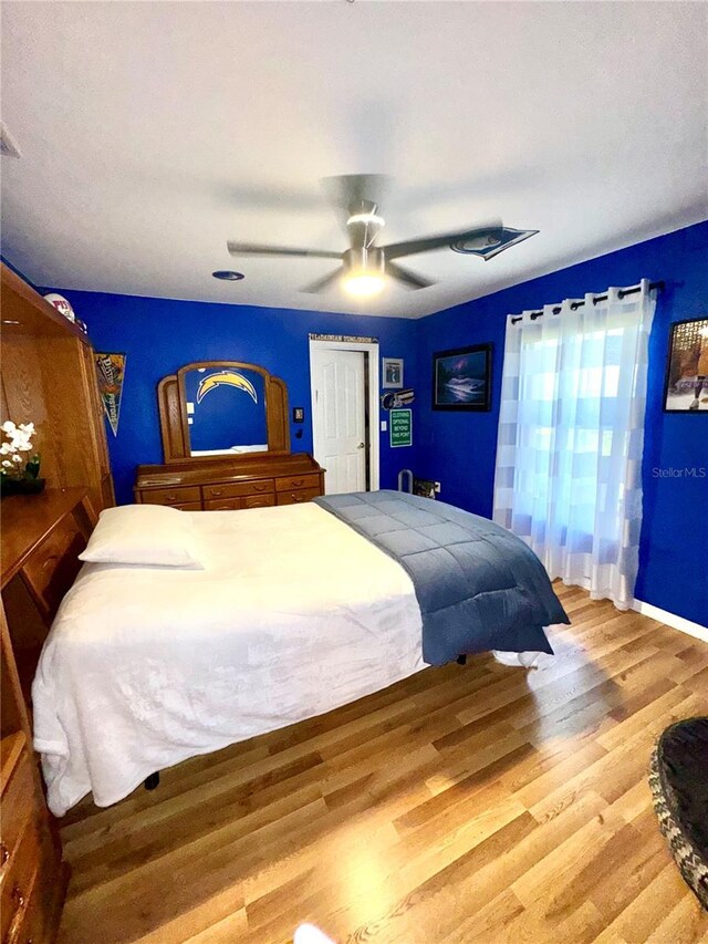 bedroom with ceiling fan, visible vents, and wood finished floors