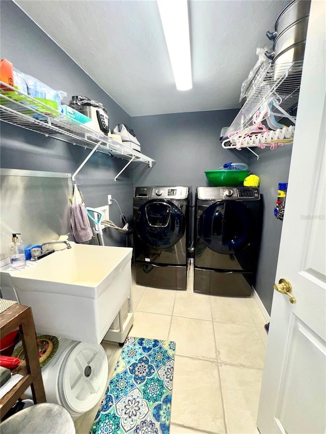 clothes washing area featuring a sink, laundry area, light tile patterned flooring, and washing machine and clothes dryer