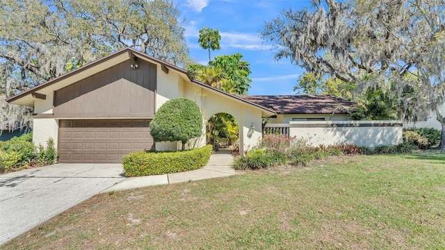 mid-century inspired home with a front yard, an attached garage, and driveway