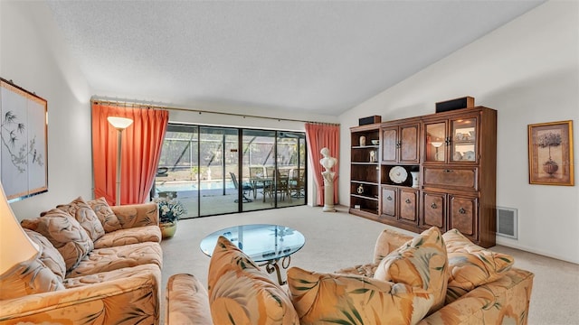 living room featuring a textured ceiling, lofted ceiling, visible vents, and light carpet