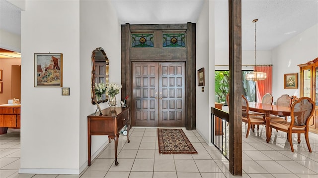 foyer with light tile patterned floors, baseboards, and a chandelier