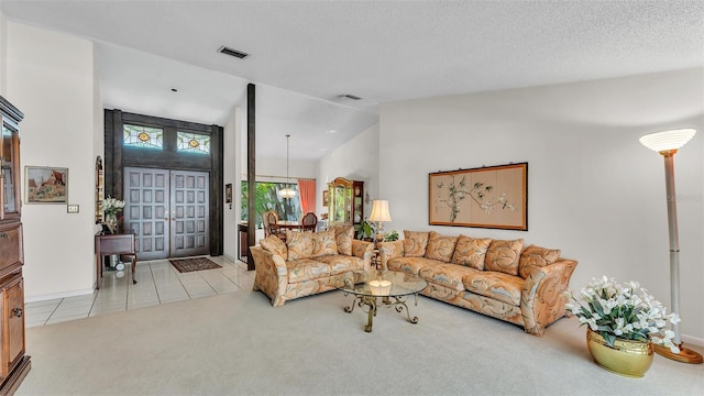 tiled living area featuring visible vents, a textured ceiling, lofted ceiling, and carpet