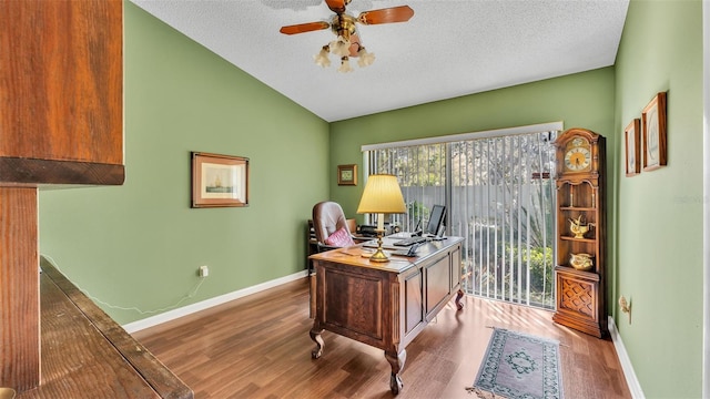 office with baseboards, lofted ceiling, wood finished floors, a textured ceiling, and a ceiling fan