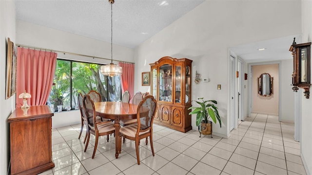 dining room with baseboards, light tile patterned floors, an inviting chandelier, a textured ceiling, and high vaulted ceiling