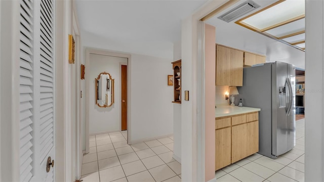 kitchen with visible vents, stainless steel fridge, light tile patterned flooring, and light brown cabinets