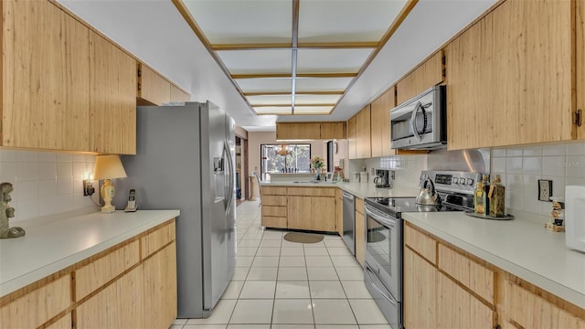 kitchen with stainless steel appliances, tasteful backsplash, light brown cabinets, and light countertops