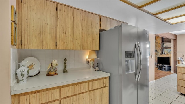 kitchen featuring tasteful backsplash, light brown cabinetry, light countertops, light tile patterned floors, and stainless steel refrigerator with ice dispenser