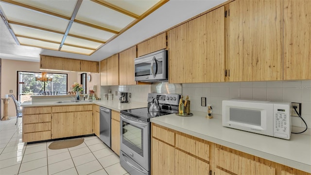 kitchen with light tile patterned floors, a sink, stainless steel appliances, light countertops, and tasteful backsplash