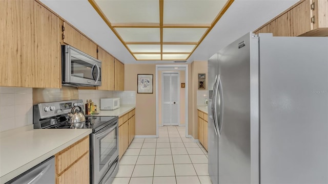 kitchen featuring light tile patterned flooring, decorative backsplash, stainless steel appliances, and light countertops