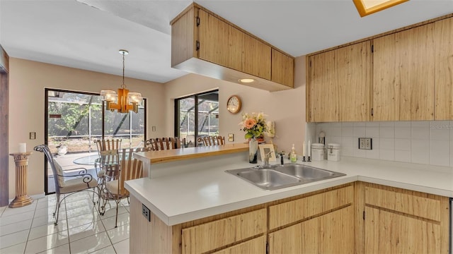 kitchen with a peninsula, light countertops, tasteful backsplash, and a sink