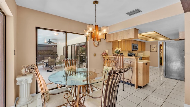 dining room featuring light tile patterned floors, visible vents, and ceiling fan with notable chandelier