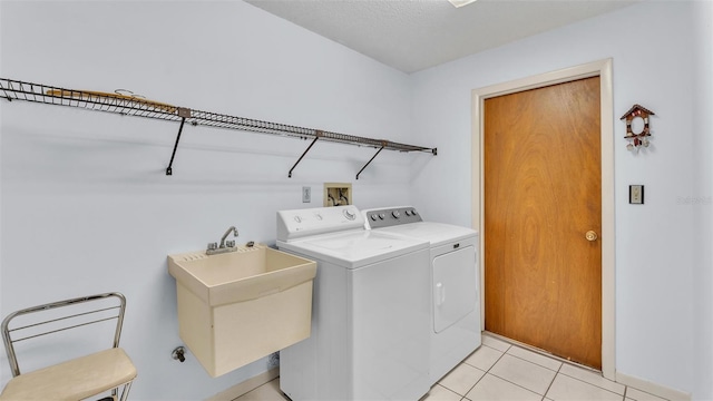 laundry area with a sink, separate washer and dryer, laundry area, and light tile patterned floors