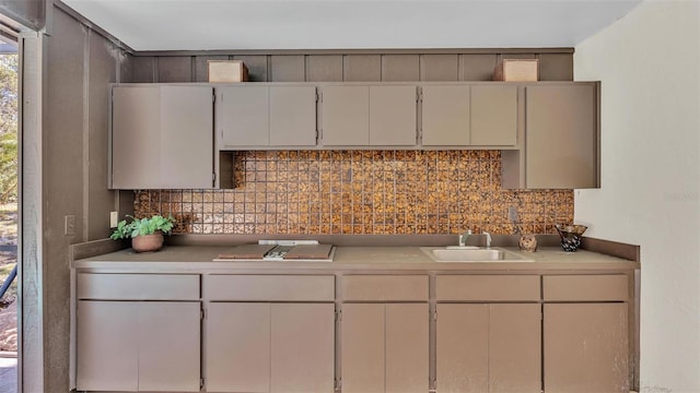 kitchen featuring a sink, stovetop, decorative backsplash, and light countertops