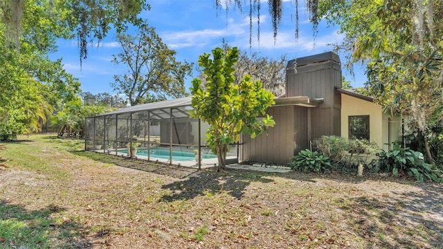 view of yard featuring glass enclosure and an outdoor pool