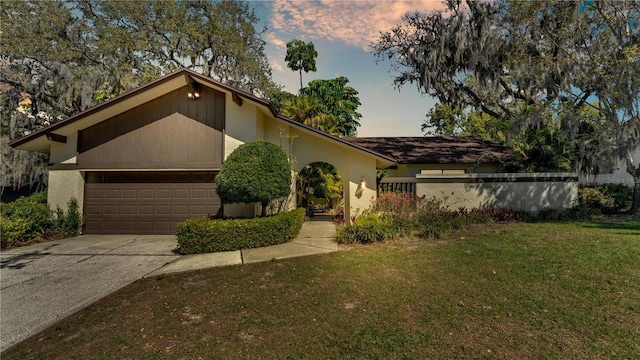 mid-century inspired home featuring stucco siding, driveway, a front yard, and a garage