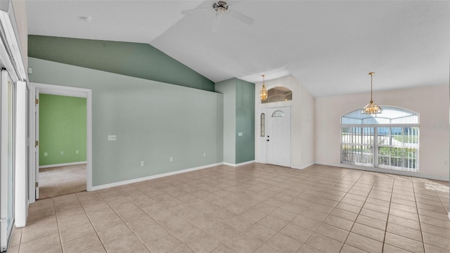 empty room featuring light tile patterned flooring, ceiling fan with notable chandelier, baseboards, and lofted ceiling