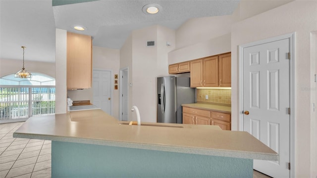 kitchen with backsplash, stainless steel fridge, light countertops, and a sink