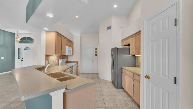 kitchen featuring white appliances, visible vents, a peninsula, a sink, and decorative backsplash