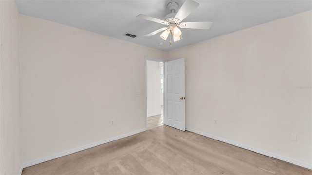 unfurnished room featuring baseboards, light colored carpet, visible vents, and ceiling fan